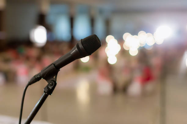 microfone na sala de concertos ou sala de conferência estilo macio e desfocado para fundo. microfone sobre a foto abstrata borrada da sala de conferência ou fundo da sala de seminário. - 13520 - fotografias e filmes do acervo