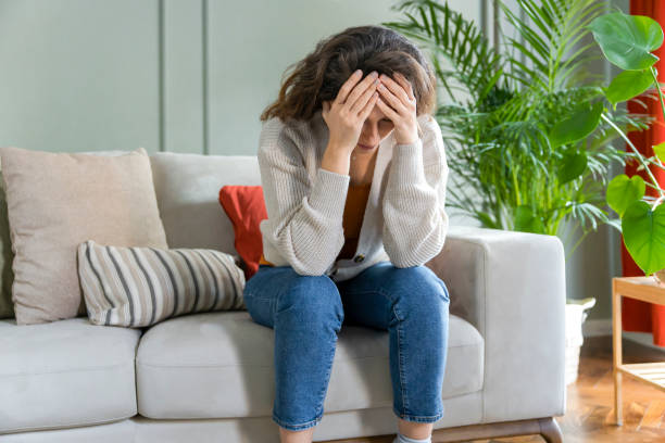 istock Depressed young woman on sofa at home 1294871688