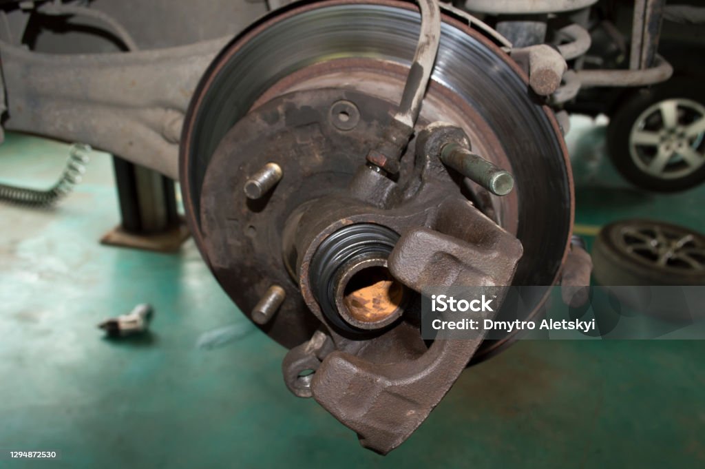 Car wheel brake caliper with traces of corrosion on the piston The brake caliper of the rear left wheel of the car, which hangs on the lift in the car repair shop with traces of corrosion on the piston Brake Stock Photo