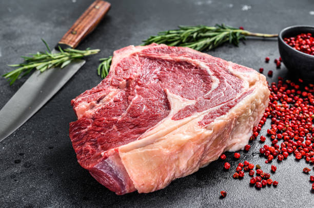 istock Ribeye on the bone or  cowboy steak. Raw Marble beef. Black background. Top view 1294876654