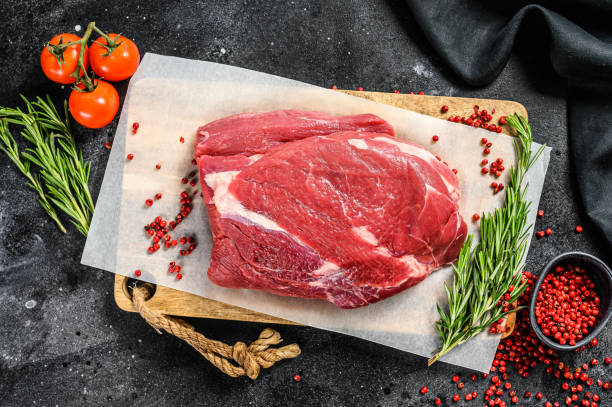 istock Raw brisket beef cut on a wooden cutting board. Black Angus beef. Black background. Top view 1294877017
