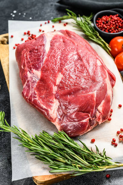 istock Raw brisket beef cut on a wooden cutting board. Black Angus beef. Black background. Top view 1294877041