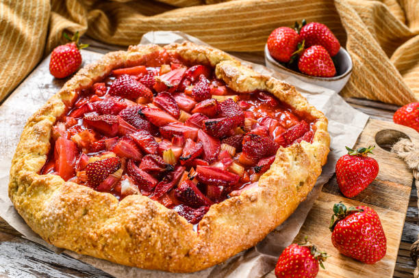Galette with strawberry and rhubarb. Homemade tart, tarte.  White wooden background. Top view Galette with strawberry and rhubarb. Homemade tart, tarte.  White wooden background. Top view. galette stock pictures, royalty-free photos & images