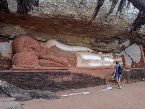 Tourist male visiting buddha on rocky temple