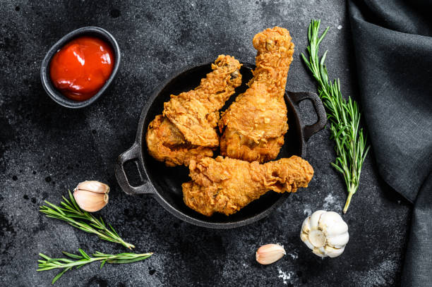 istock Fried crispy chicken legs, drumstick in a pan. Black background. Top view 1294882227