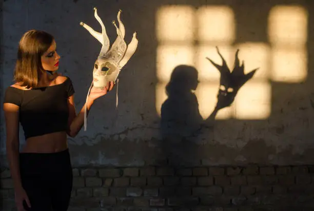Woman wearing carnival mask casting shadow on the wall.