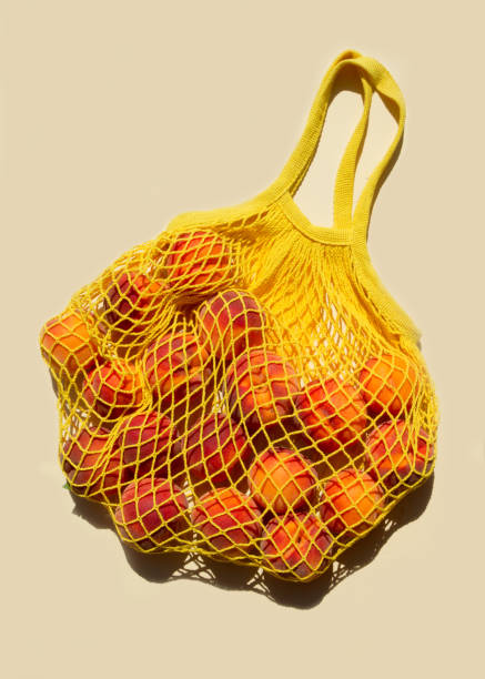 istock Ripe peaches in a mesh bag or string bag on light yellow background. Flat lay. Zero waste. 1294885588