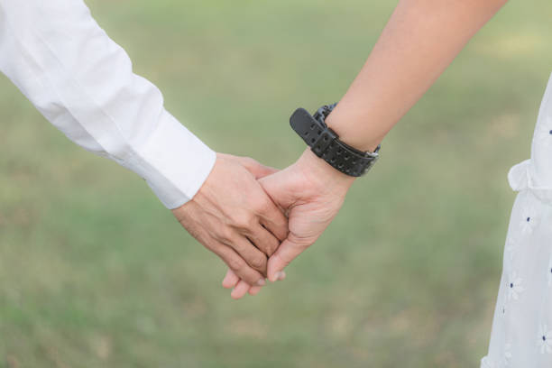 Couple hold hands in green field on sunset