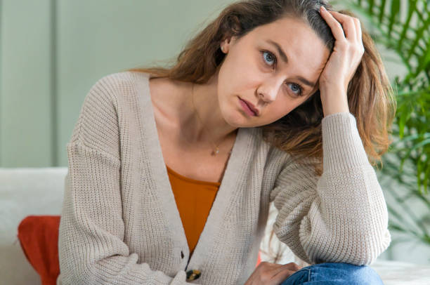 istock Depressed young woman on sofa at home 1294888775