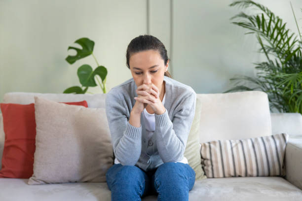 istock Depressed young woman on sofa at home 1294891521