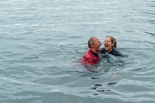 A couple in the sea at Polperro, Cornwall. They are laughing while embracing each other.