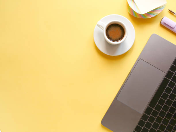 istock flat lay composition with laptop, pen, coffee on yellow background. Concept remote study and work at home, telework, freelance, quarantine. Coffee break, office table. Copyspace 1294893550