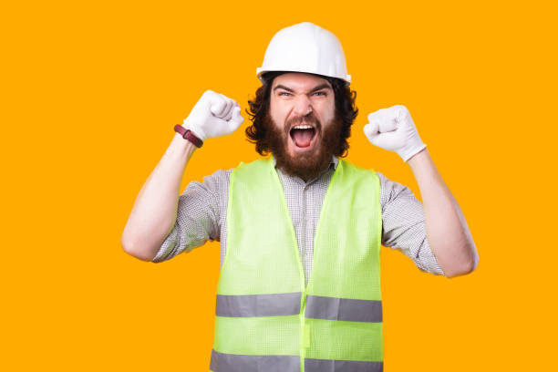istock An upset young engineer is looking at the camera screaming with both hands up near a yellow wall 1294894052