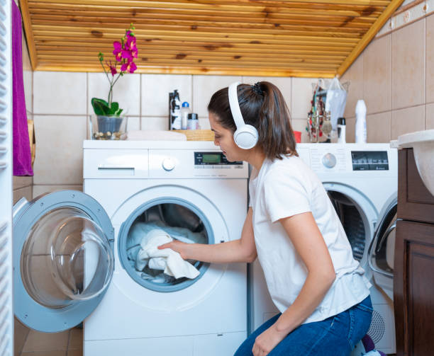 la joven está recogiendo toallas y ropa de la secadora de ropa de lavandería en el baño.  día de lavandería - all laundry detergent audio fotografías e imágenes de stock