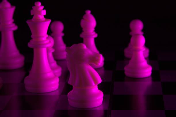 istock Chess pieces in a purple light with black background 1294900065