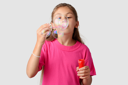 Happy little girl playing with soap bubbles in a studio