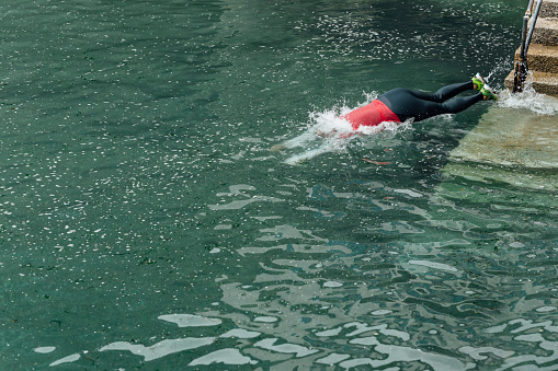 stcw life raft training maritime course in the swimming pool, people wearing waterproof suits