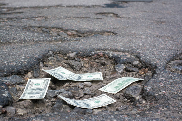 道路上のポットホールでドル紙幣 - money pit ストックフォトと画像