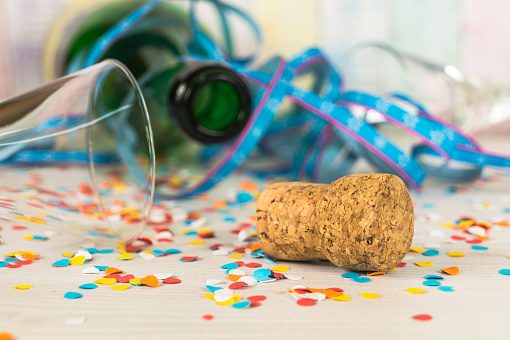 Champagne bottle and bunch of confetti on brown background. Flat lay concept.