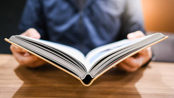 istock Male university student reading book in college library. Self learning and leisure activity. Education concept 1294910941