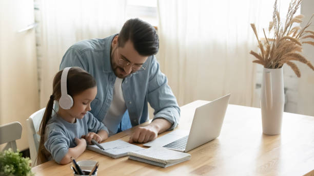 istock Caring father helping little daughter with school homework at home 1294912686