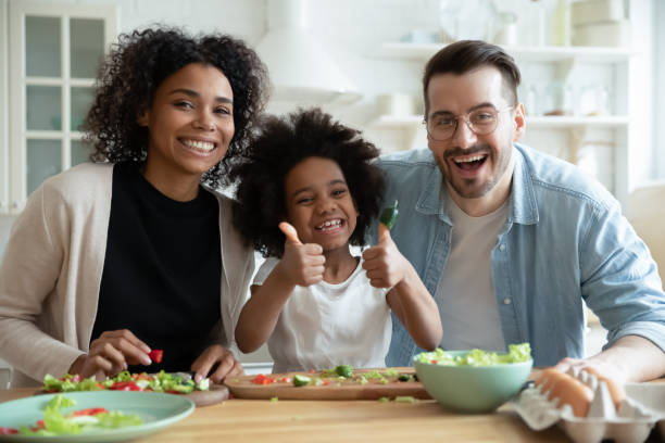 kopf schuss porträt glücklich multiracial familie mit kind in der küche - daumen fotos stock-fotos und bilder