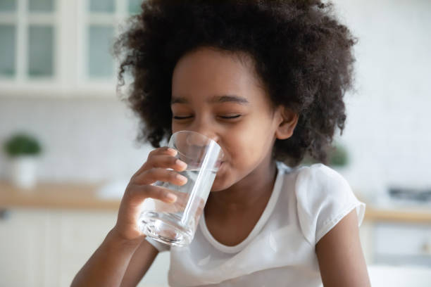 Pretty little African American girl drinking fresh water in kitchen Pretty little African American girl drinking fresh water in kitchen close up, cute preschool child kid holding glass of pure mineral water, enjoying, healthy lifestyle and refreshment concept drinking water stock pictures, royalty-free photos & images