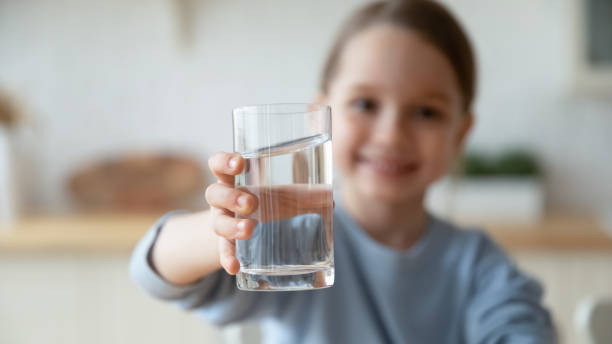 Close up little girl holding water glass, offering to camera Close up smiling little girl holding glass of pure mineral water, offering to camera, cute pretty child kid recommending healthy lifestyle habit, drinking clean aqua for refreshment drinking water stock pictures, royalty-free photos & images