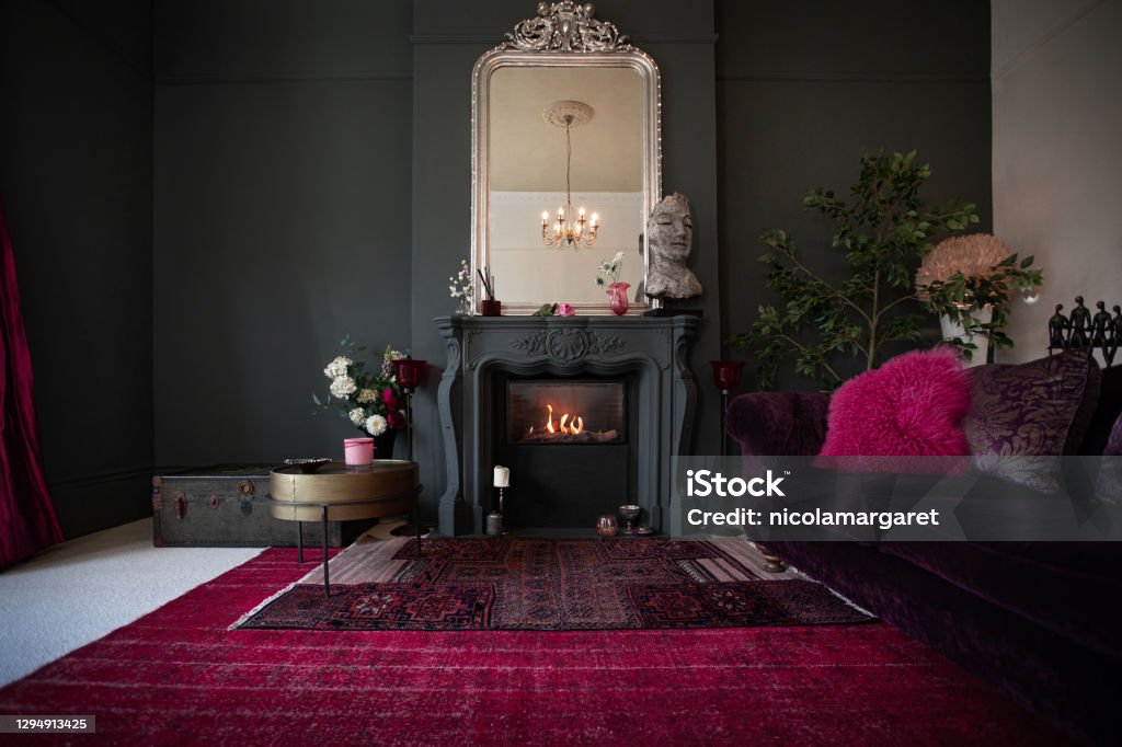 Living room with dark walls and authentic fireplace Contemporary decor, bold colour palette, luxurious textiles Magenta Stock Photo