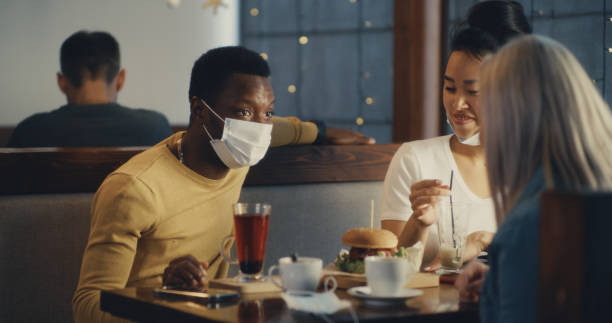 istock Black man in mask speaking with multiethnic women in cafe 1294916185