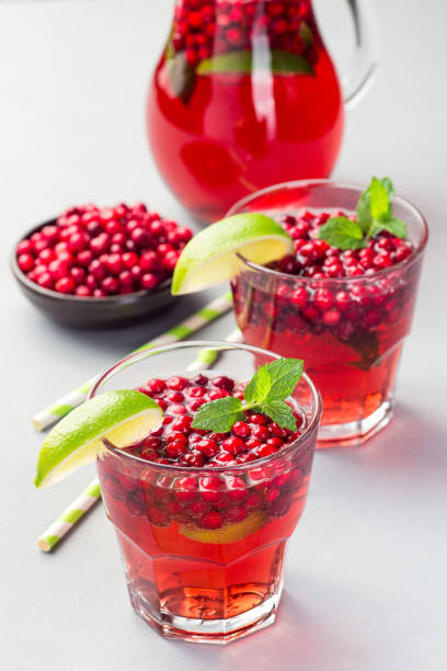 istock Lingonberry and lime punch or limeade in glass and pitcher on gray background, vertical 1294917013