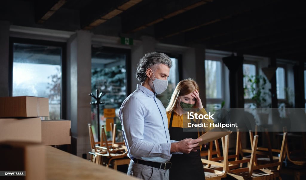 Frustrated owner with waitress in closed cafe, small business lockdown due to coronavirus. Frustrated owner with waitress talking in closed cafe, small business lockdown due to coronavirus. Business Stock Photo