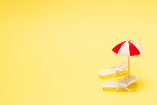 istock Two sun loungers and a red umbrella on a yellow background. 1294918094