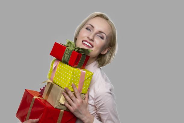 istock Happy woman with gift boxes on gray background. 1294920050