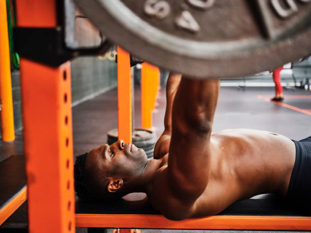 istock Man Working Out in a Gym with Barbell and Weights 1294920455