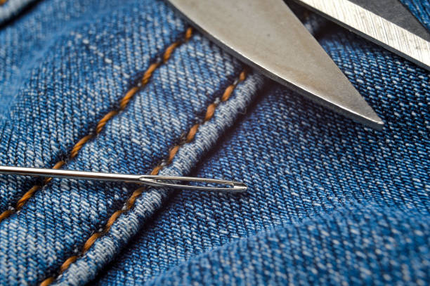 istock sewing needle and scissors lie on blue jeans. close-up. 1294920531