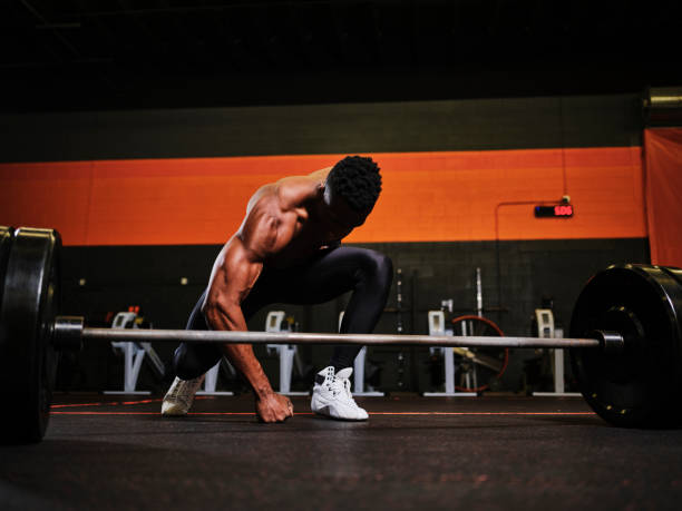 istock Man Working Out in a Gym with Barbell and Weights 1294922246