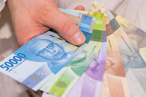 валюта индонезии, рупия, файл банкнот, удерживаемых в руке - human hand beak currency stack стоковые фото и изображения