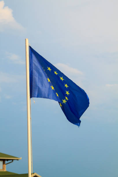 istock European Union flag on a blue sky with clouds background 1294923199