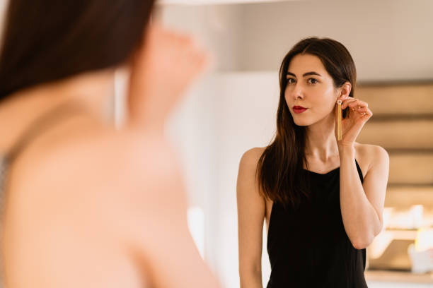 Lady wears beautiful black dress looking into the mirror stock photo