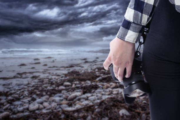 istock Photographer Holding a Camera On a Stormy Coastline 1294925850