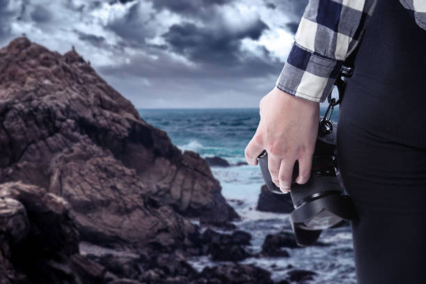 istock Photographer Holding a Camera On a Stormy Coastline 1294925888