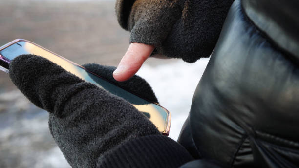 istock Man playing an AR game on mobile phone during Winter with cutoff gloves 1294928486