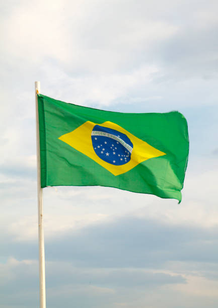 istock Brazilian flag on a blue sky with clouds background 1294929033