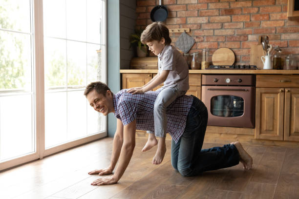istock Young dad crawling by warm floor holding son on back 1294931297