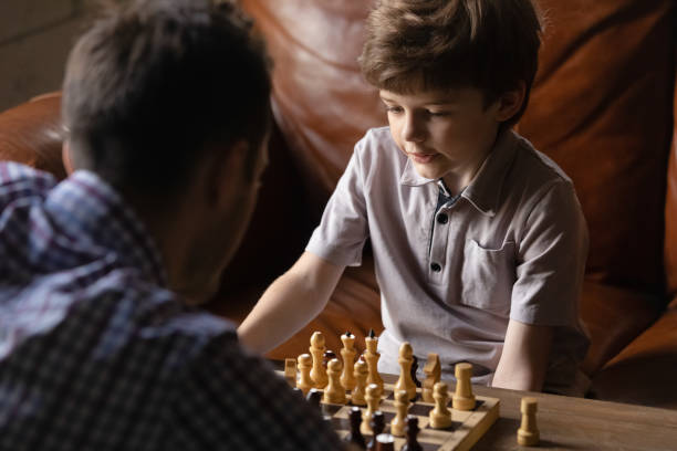 istock Attentive boy junior pupil playing chess with young male coach 1294931304
