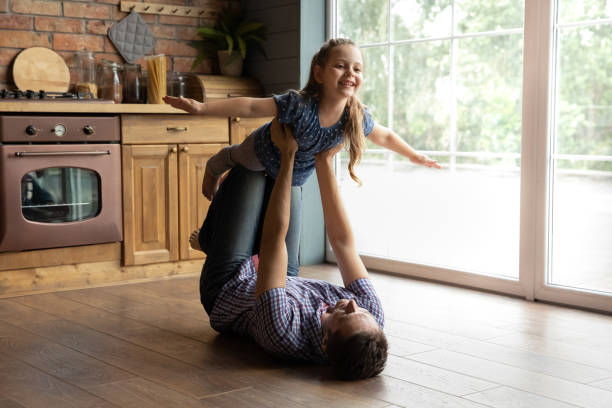 istock Young daddy lying on back lifting junior daughter in air 1294931312