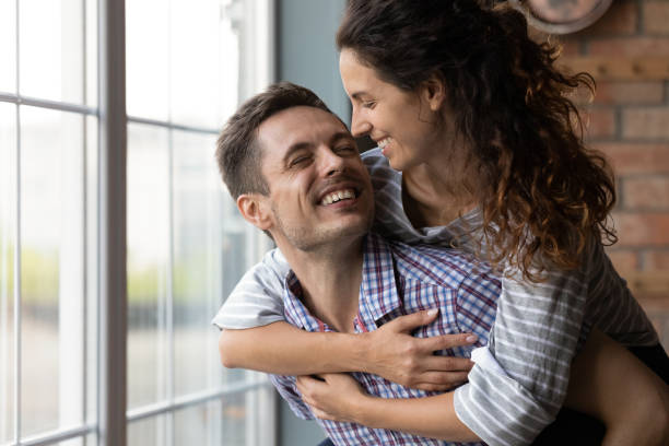 istock Affectionate young husband holding beloved laughing wife on back indoors 1294931330