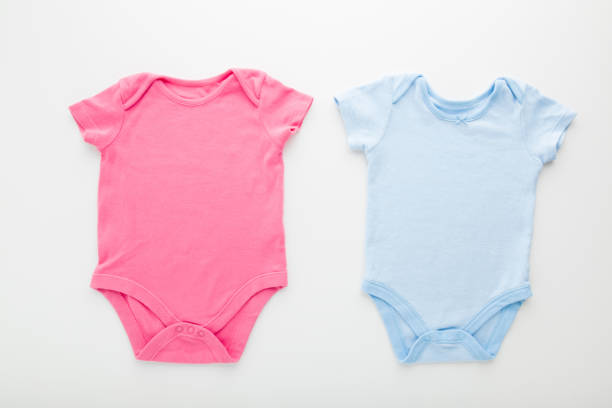 istock Pink and blue baby bodysuits on light gray table background. Closeup. Empty place for text or logo on apparel. Top down view. 1294932438
