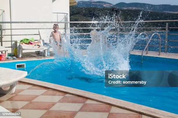 Water Splashes After The Young Mans Jump Into The Pool Stock Photo - Download Image Now